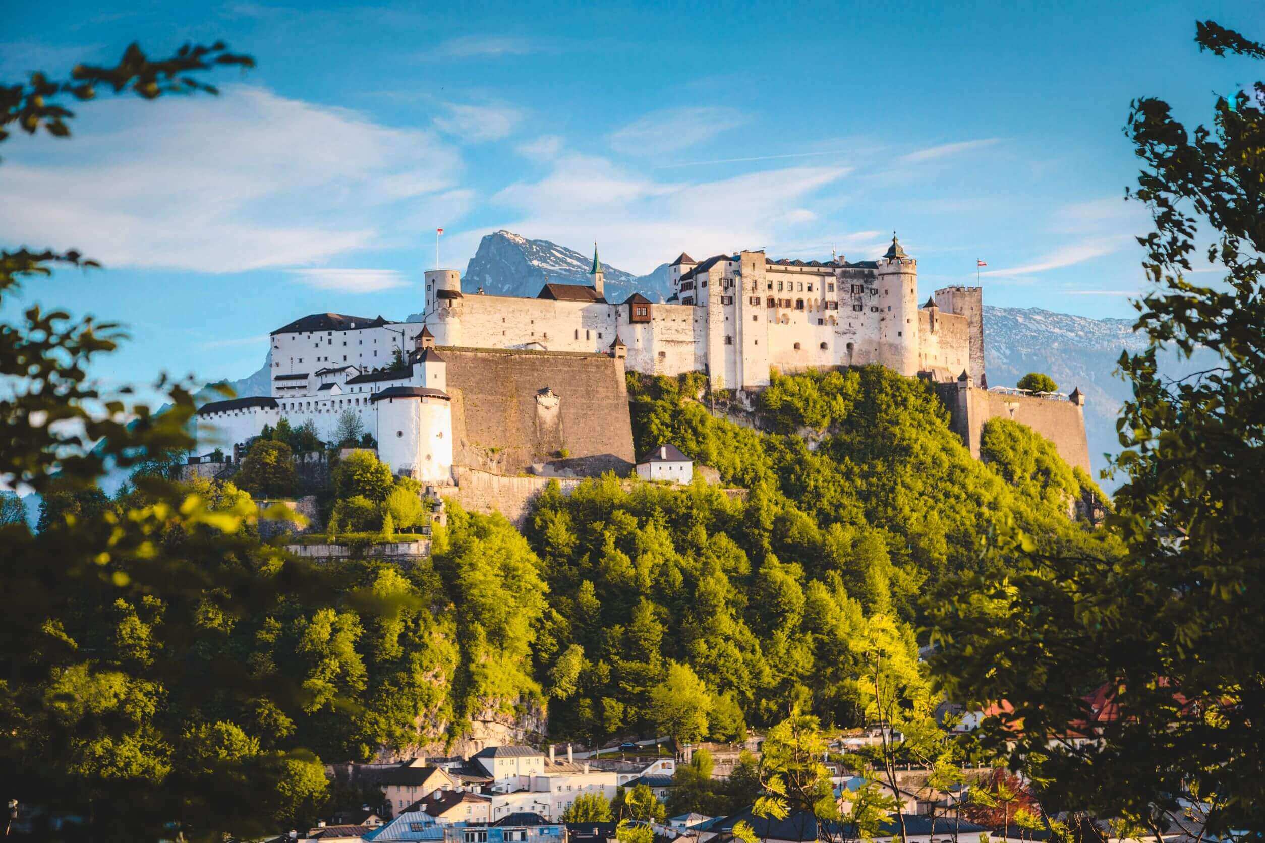 classic panorama view of famous Hohensalzburg Fortress under blue skies with mountain in background