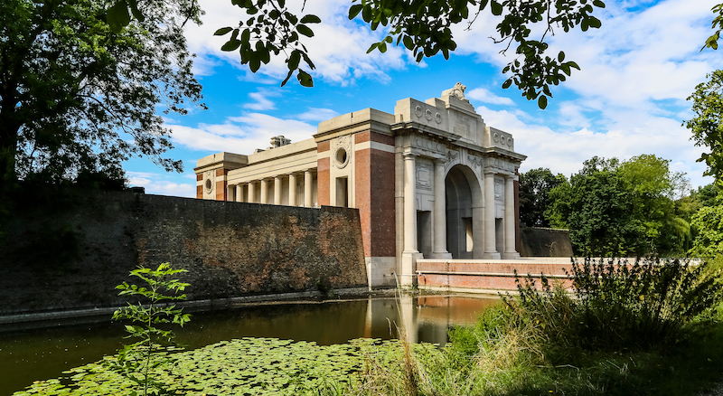 the Menin Gate war memorial, Ypres, framed by trees and a canal