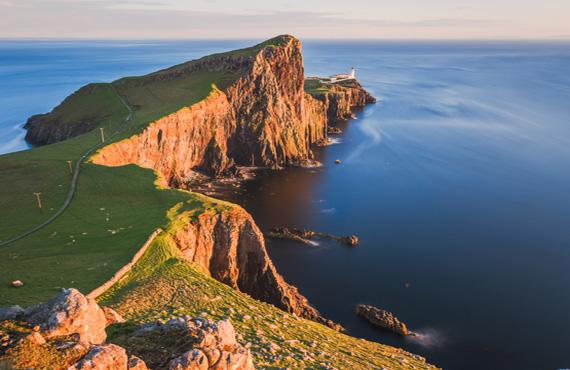 A coastal view of the cliffs of the Isle of Skye during sunset.