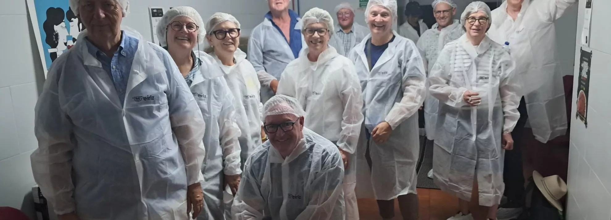 A small group of mature people wearing white overcoats and smiling at the camera.