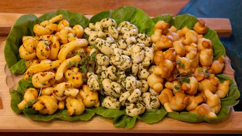 A platter of different exotic cheeses on leaves during a cheese tasting experience.
