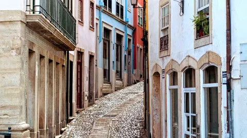 A winding cobblestone road curves past the multi-colour buildings in Coimbra.