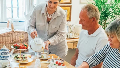 A server pours tea for travellers experiencing an afternoon tea-time.