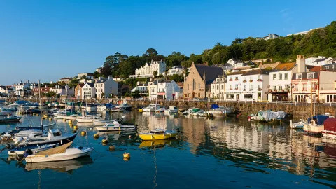 A view of Jersey's port district, with small pleasure craft and sailing vessels dotting the coastline.