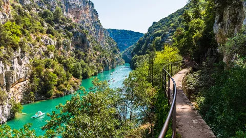 A view of the Verdon Gorge, with paddle boats and people swimming in the verdon river.