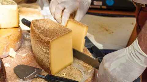 A Man cuts a slice of authentic Manchego Cheese during a Cheese experience.