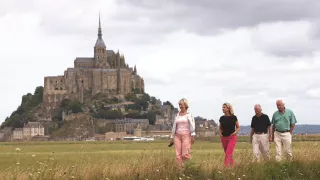 Travelers traversing the field with Mont St Michael in the background.