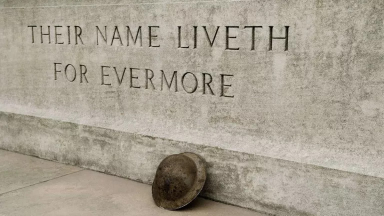 WWI monument with 'their name liveth for evermore' etched into stone with helmet leaning against it