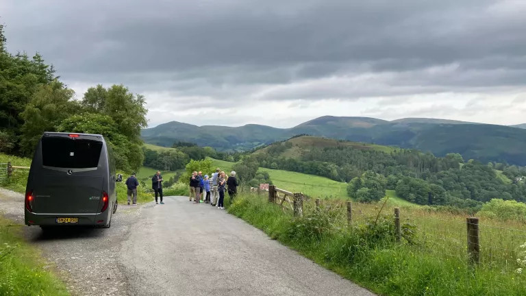 a tour group outside of the coach enjoying the view
