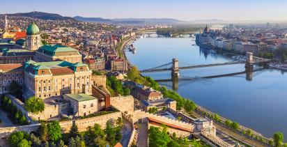 A view of Budapest, with Buda Castle featuring prominently in the foreground overlooking the Rhine River.