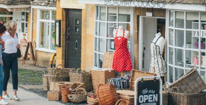 Two travelers walking down the main road of Broadway in Worcestershire past the crafts shops.