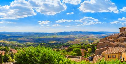 A view from a hill overlooking the walled city of Volterra during the day.