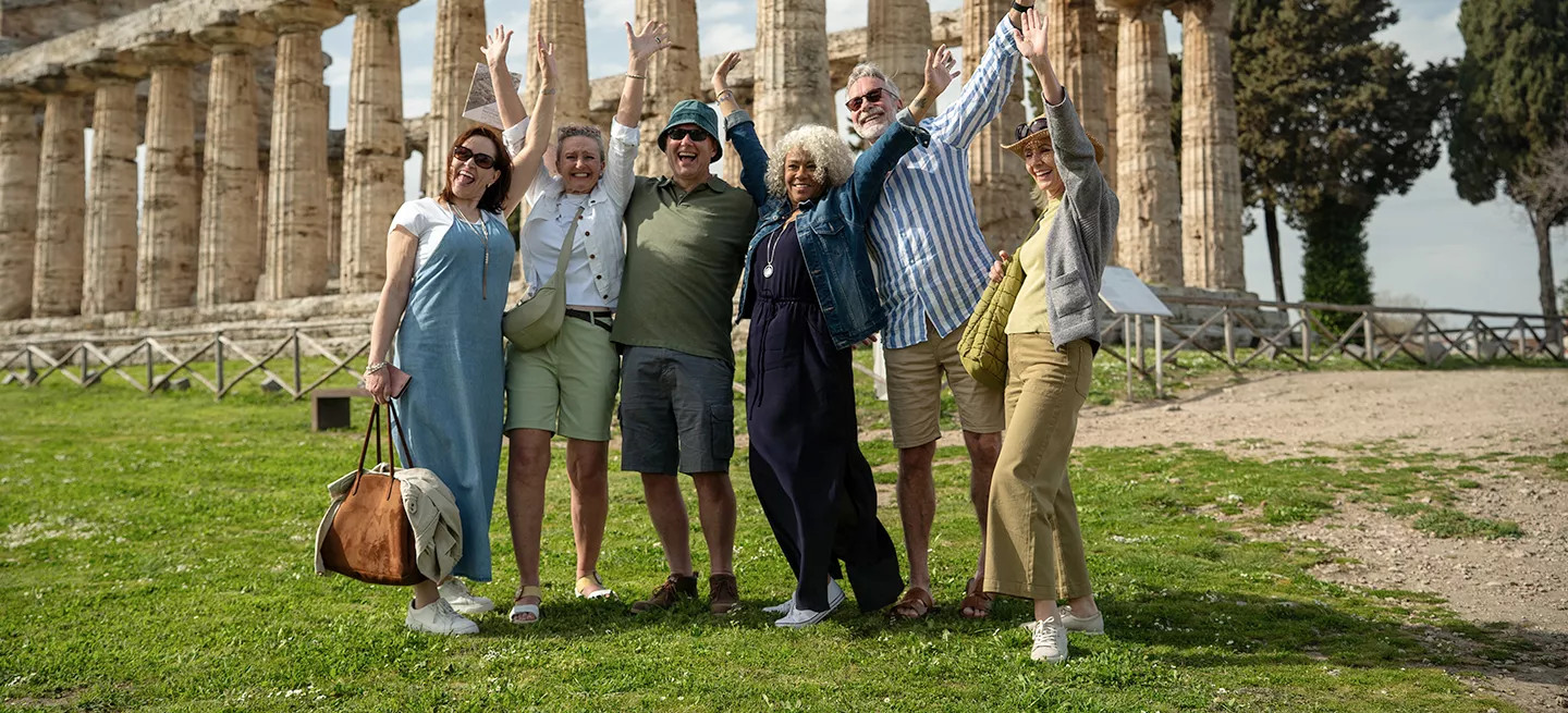 A group of travellers pose for a photo in front of Italian ruins.